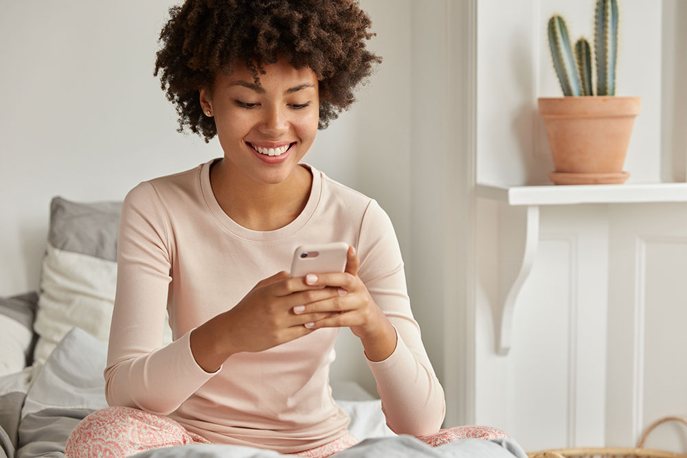 Female using phone on bed